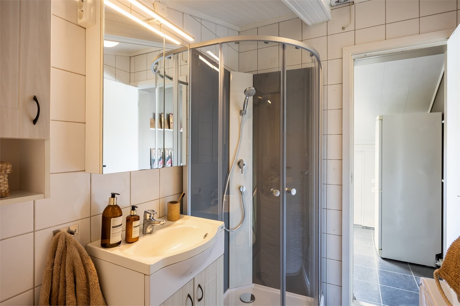 Innenfor badet er det et lite skap som praktisk kan benyttes til lagring.
