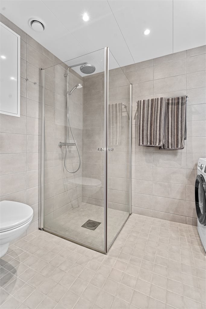 Badet er utstyrt med servant, servantskap, veggmontert wc, innfellbare dusjdører og opplegg for vaskemaskin.