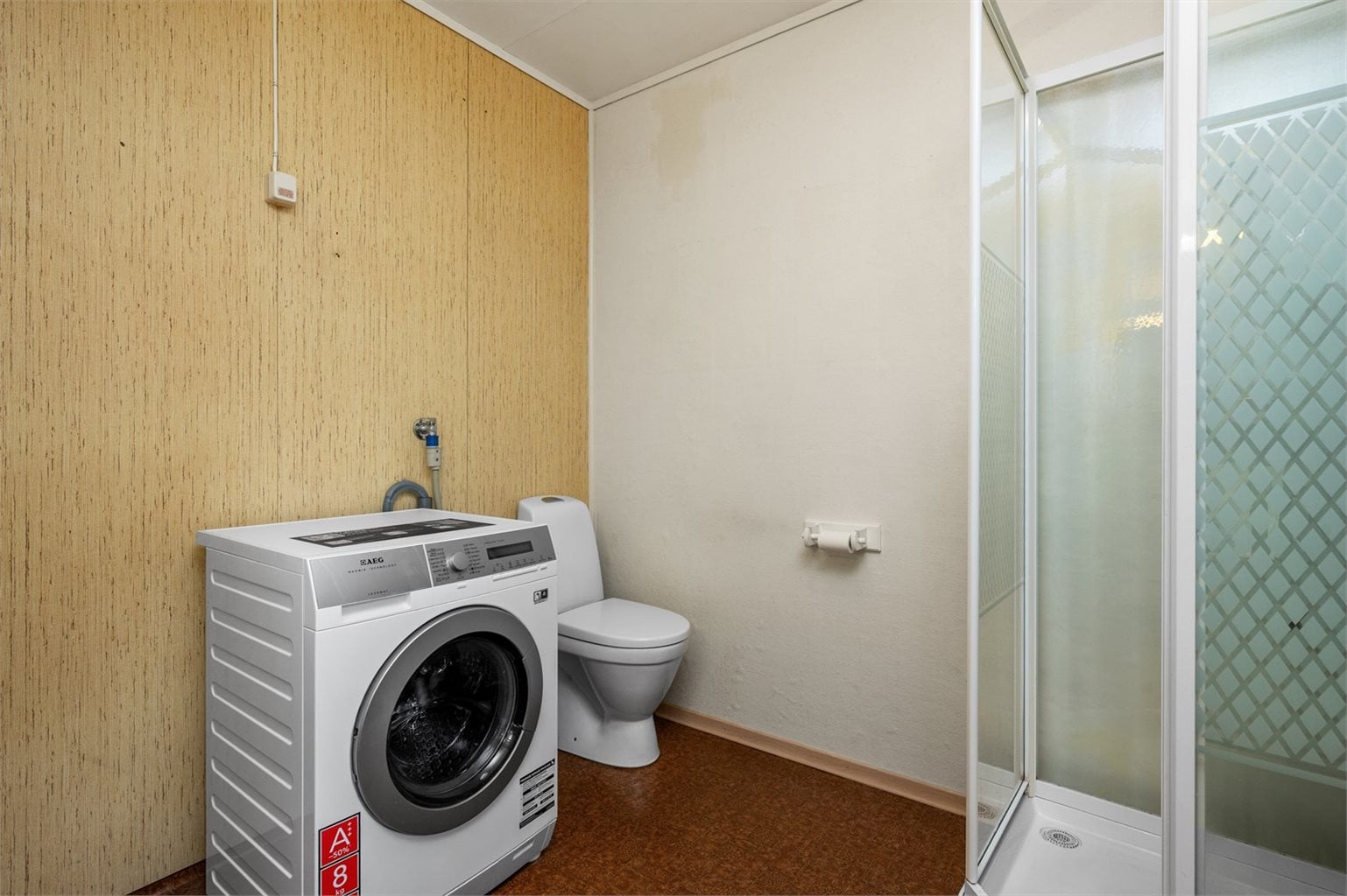 Badet er utstyrt med dusjkabinett, vaskemaskin, toalett og servant.