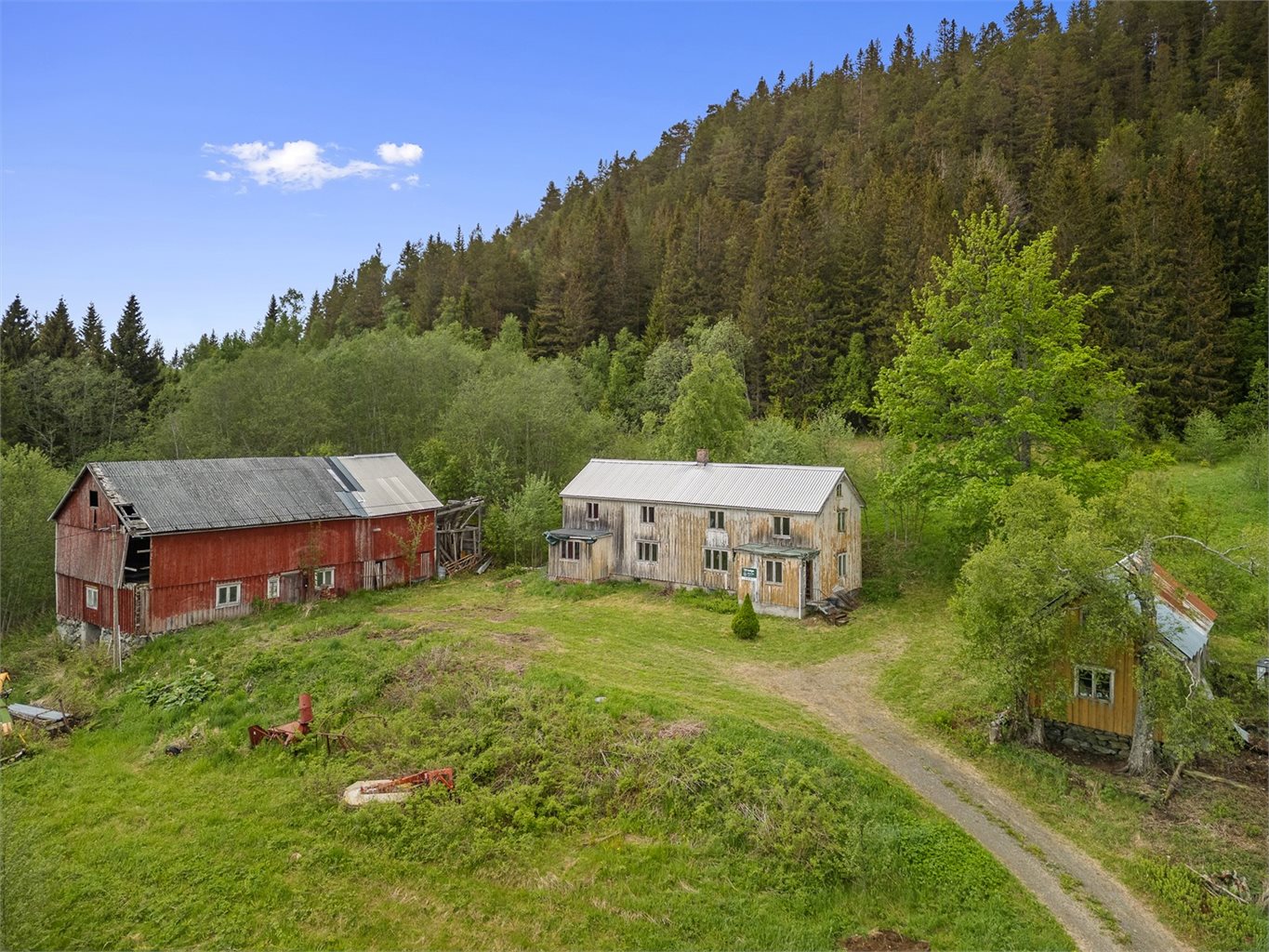 Rundt tunet står det et romslig våningshus, et eldre uthus og en rødmålt låve.