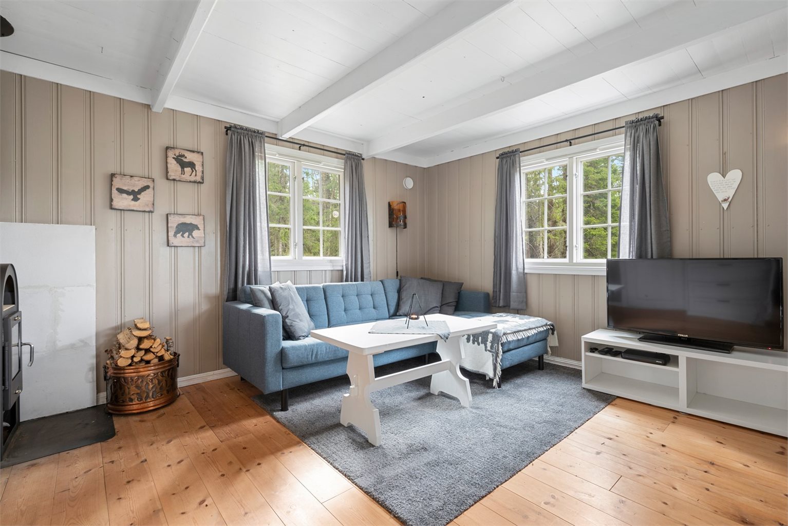 Dagslyset strømmer inn via store sprossevinduer i tre himmelretninger i stuen.