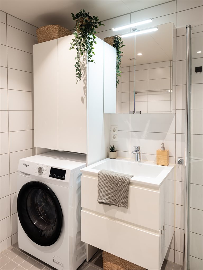 Badet byr på servant, servantskap, innfellbare dusjsdører, veggmontert wc og opplegg for vaskemaskin.