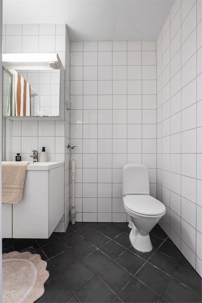 Badet er innredet med dusjkabinett, servant med underskap og opplegg for vaskemaskin
