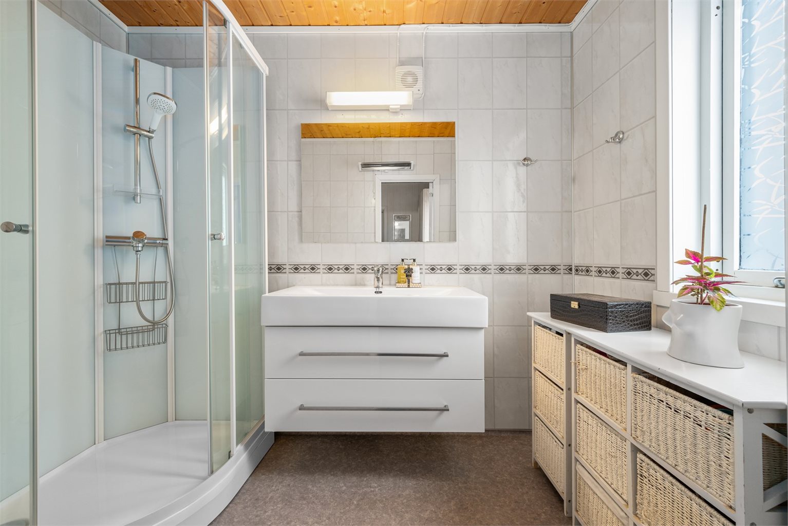 Badet er utstyrt med dusjkabinett, mekanisk avtrekk, baderomsinnredning, og WC.