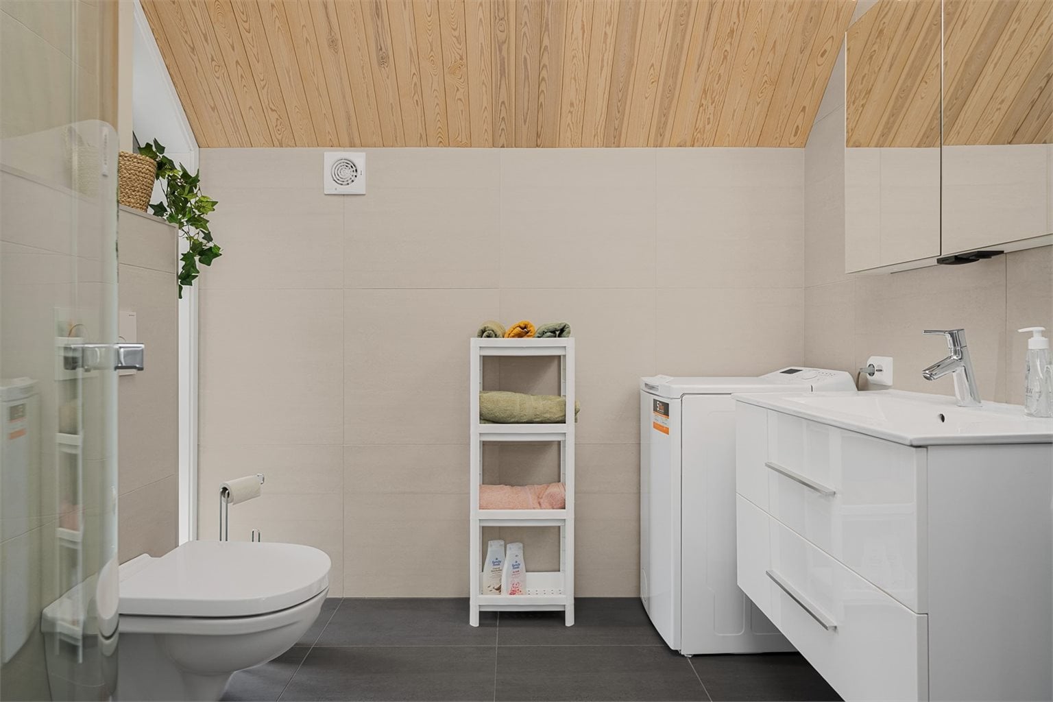 Bad med innredning, dusj-hjørne, wc og opplegg for vaskemaskin.