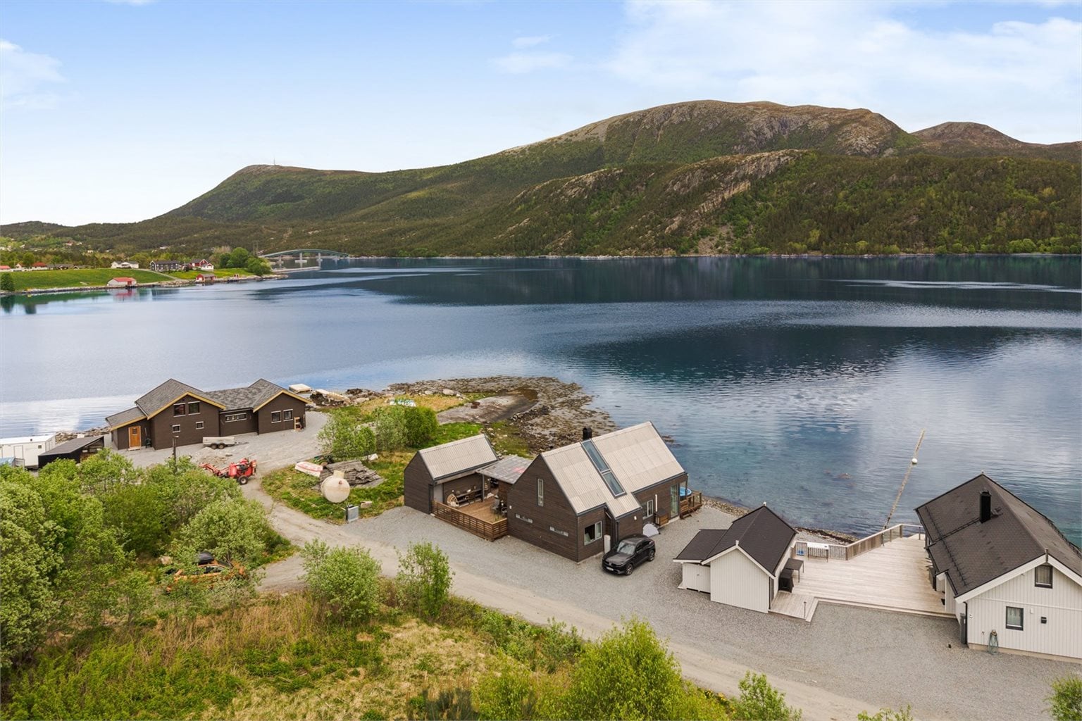 Dronebilde med hytta i midten, Dromnessundet og fjellet Fonna (et populært turmål) i bakgrunnen.