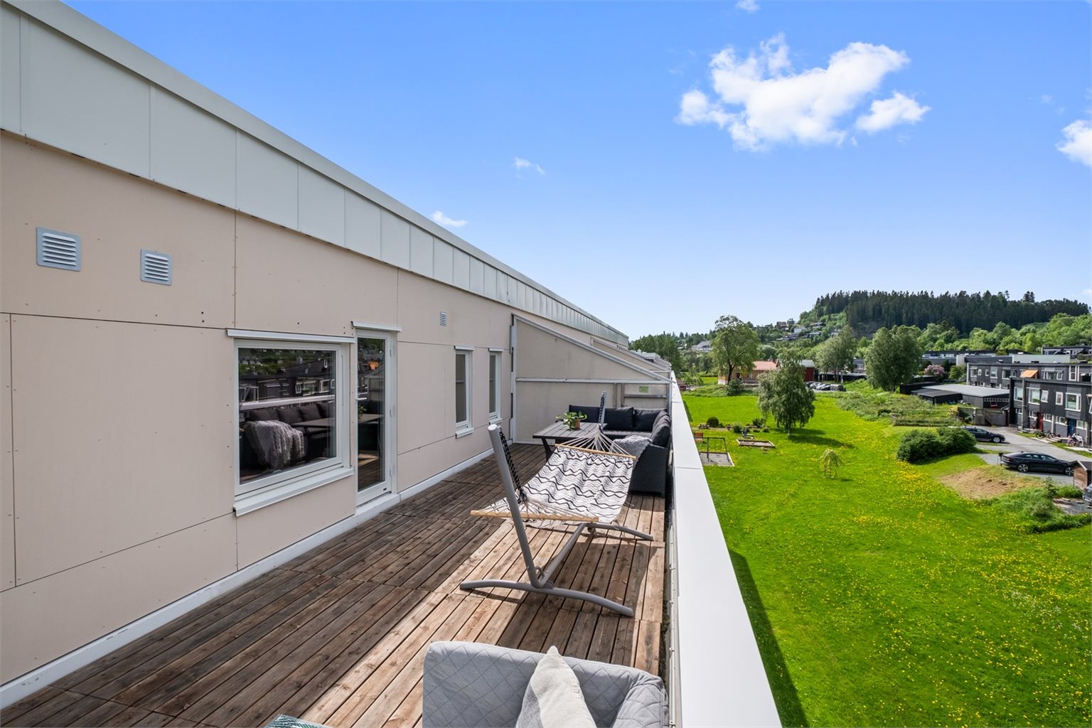 Stor og moderne terrasse som utvider leilighetens oppholdsareal og skaper en sømløs overgang mellom inne- og uteområde.