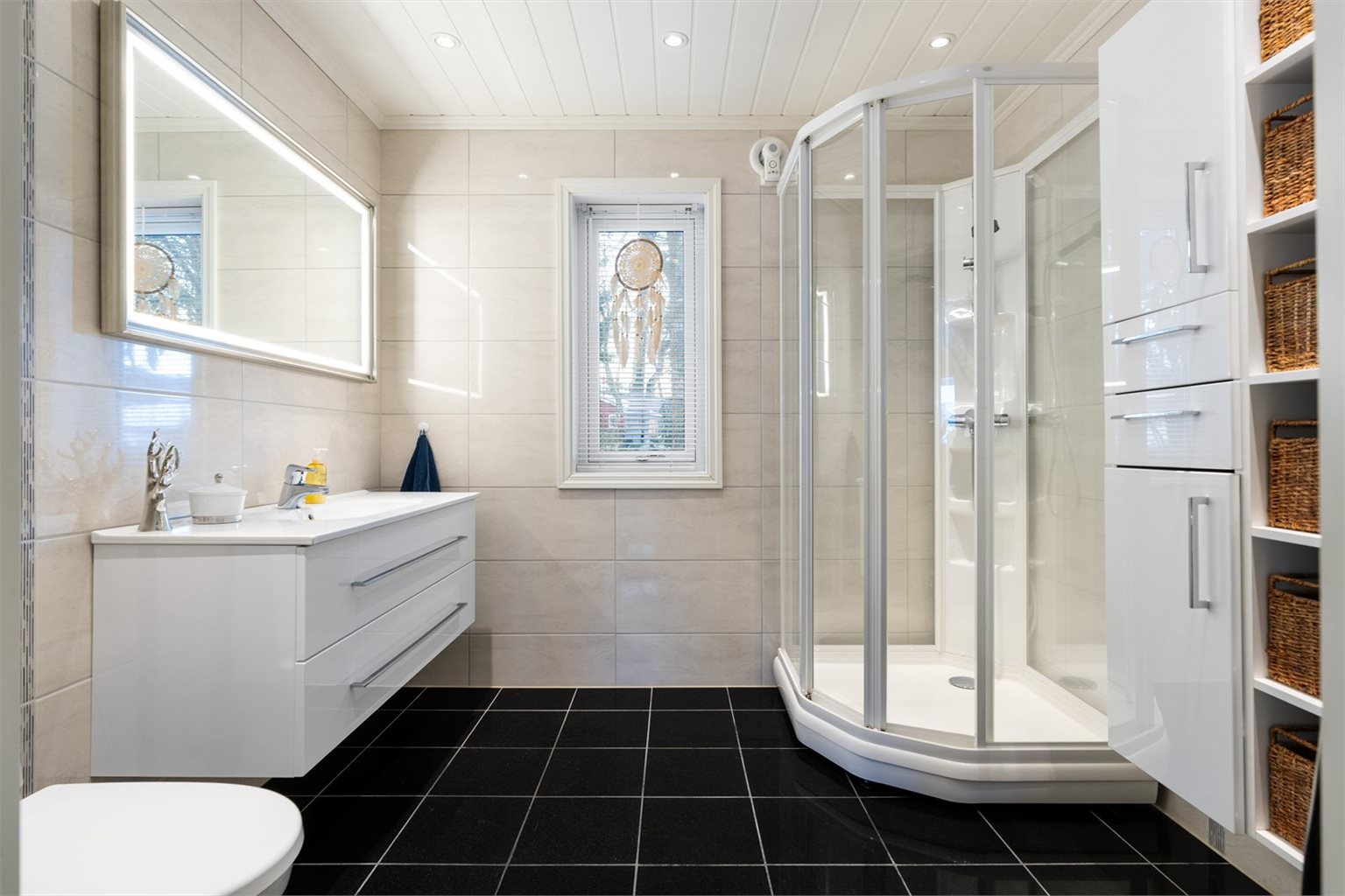 Badet i 2. etasje på 6 m² er flislagt, lyst og meget funksjonelt med vegghengt toalett og romslig dusjkabinett