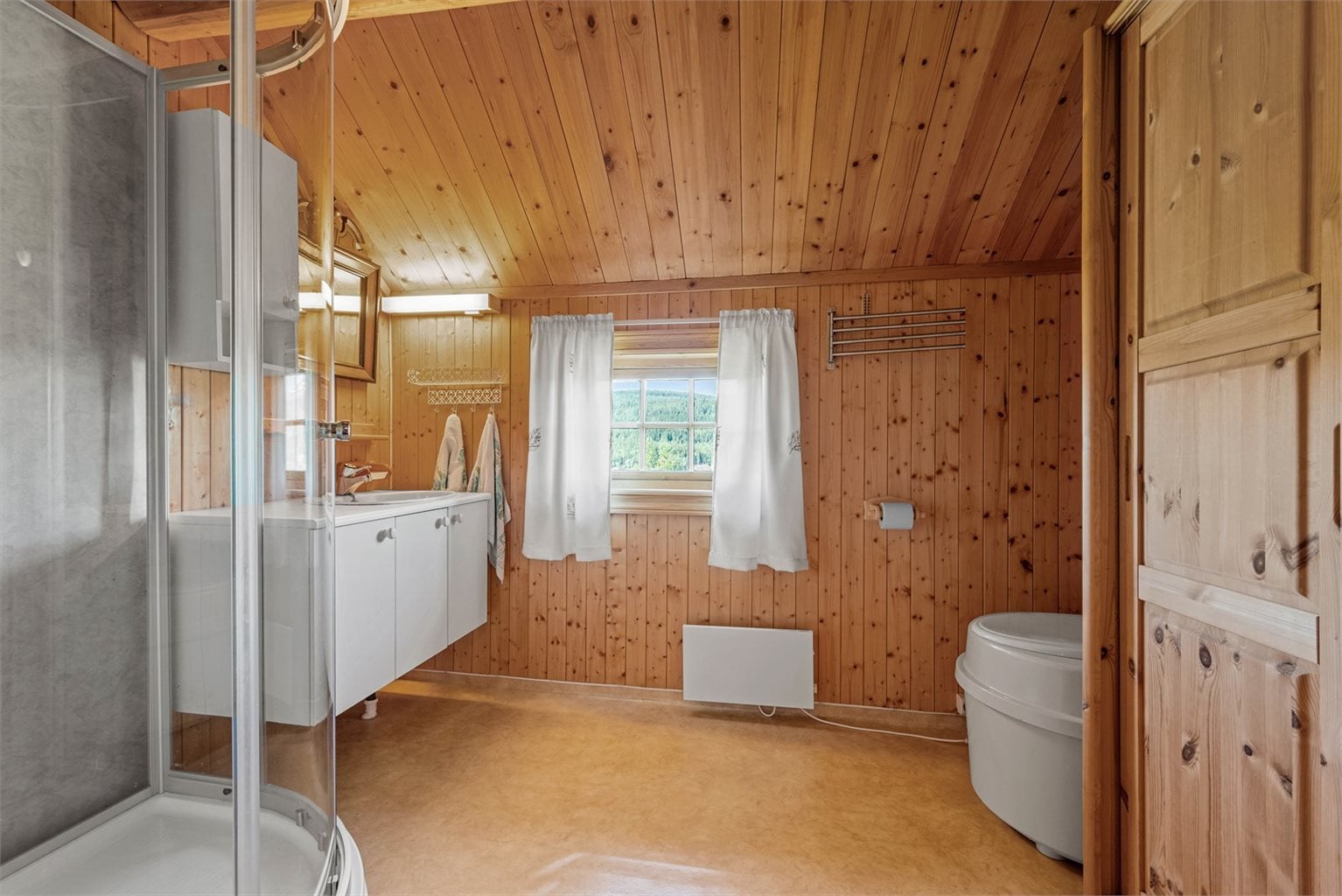 Bad utstyrt med belegg på gulv, panel og våtromstapet på vegger. 